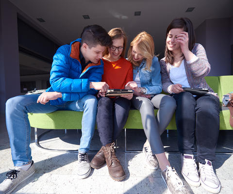 Neljä opiskelijaa katsovat tabletista jotakin.