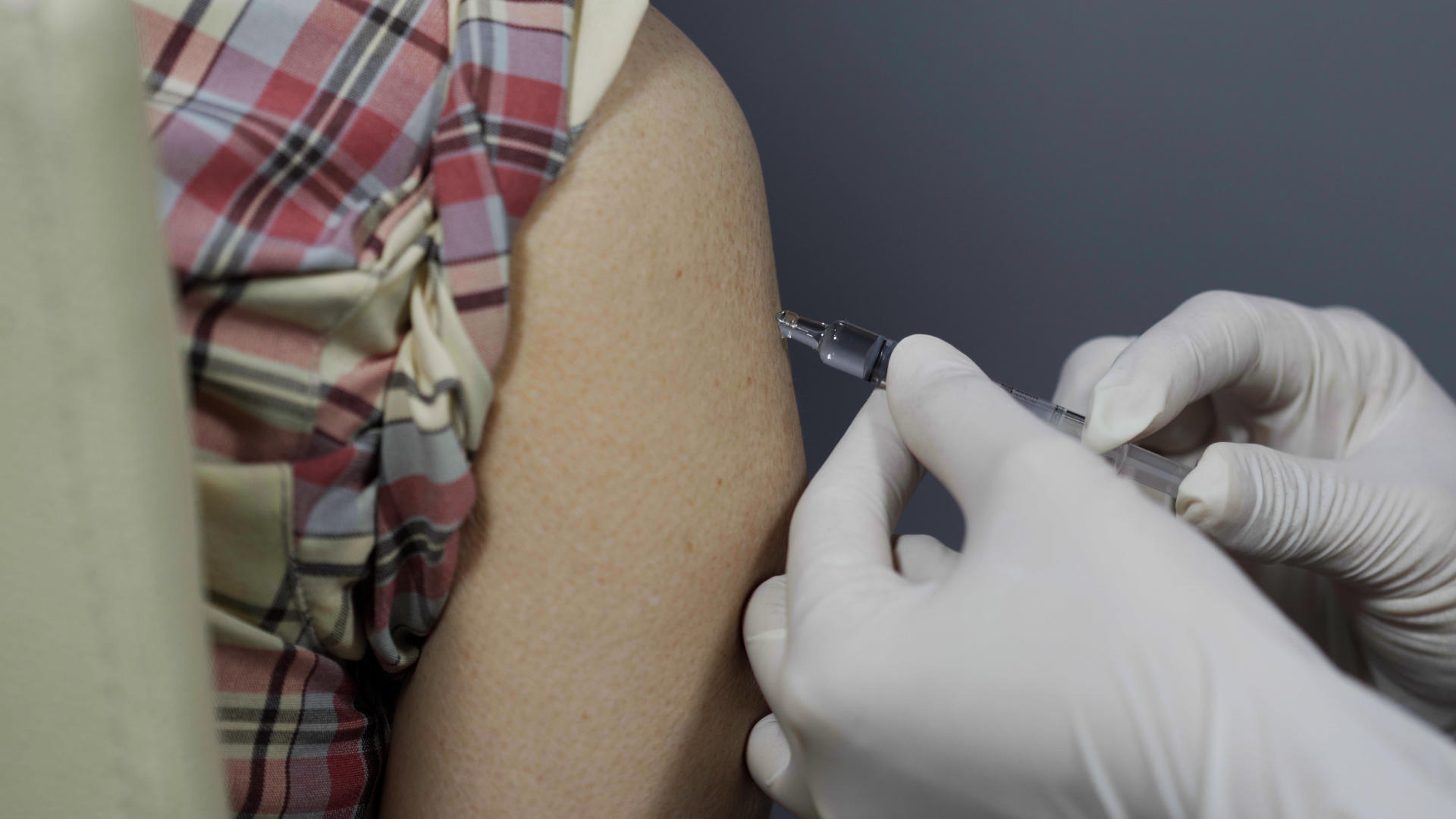 Hoitaja antaa rokotusta käsivarteen