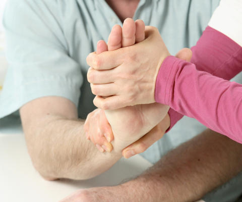 Fysioterapeutti hoitaa potilaan kättä.