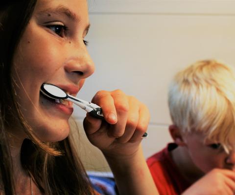 Tyttö ja poika pesevät hampaita.