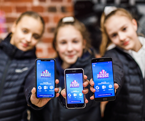Kolme nuorta pitelee puhelimia, joissa Nuorisopassi-sovellus.