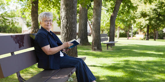 nainen istuu puiston penkillä