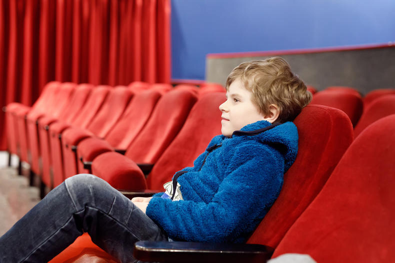 Pieni poika istuu yksinään elokuvateatterissa.
