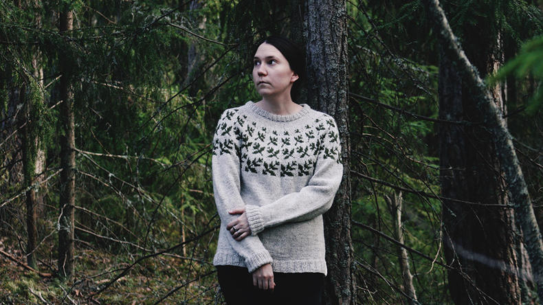 Raisio-neuleen suunnittelija Jenna Kostet metsässä.