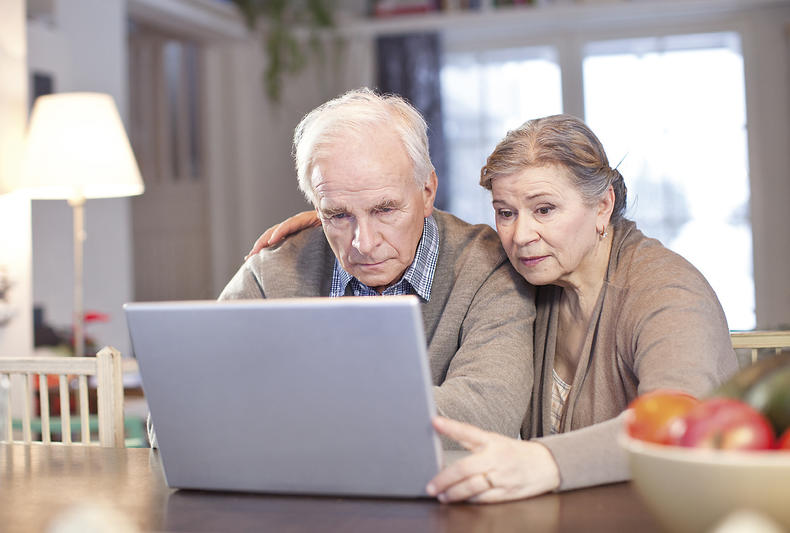 Seniori-ikäiset mies ja nainen katsovat yhdessä tietokoneen näyttöä.