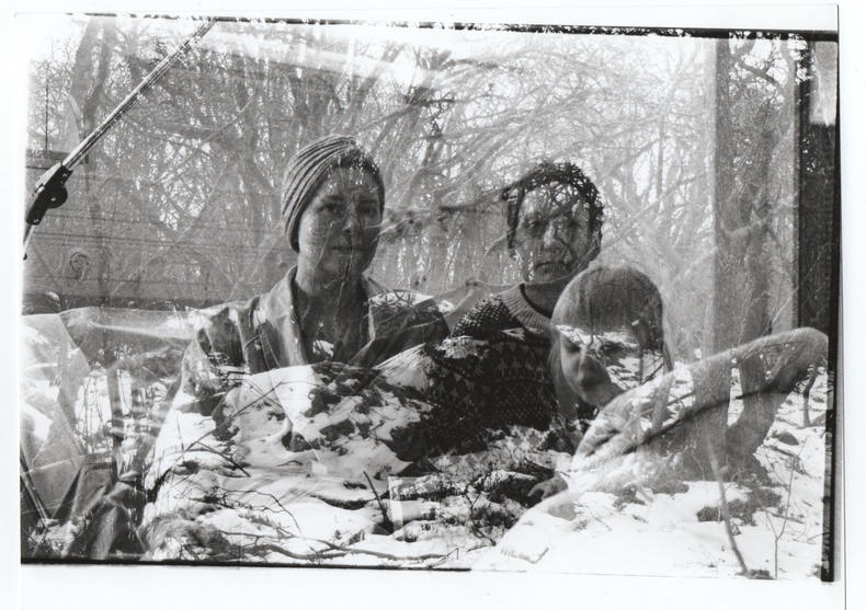 Mustavalkoinen polaroid-valokuva, jossa on kaksi valokuvaa yhdistetty. Kolme henkilöä sekä puiden oksat.